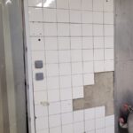Mur en faïence dont plusieurs carreaux se sont descellés, support à nu, en cuisine collective