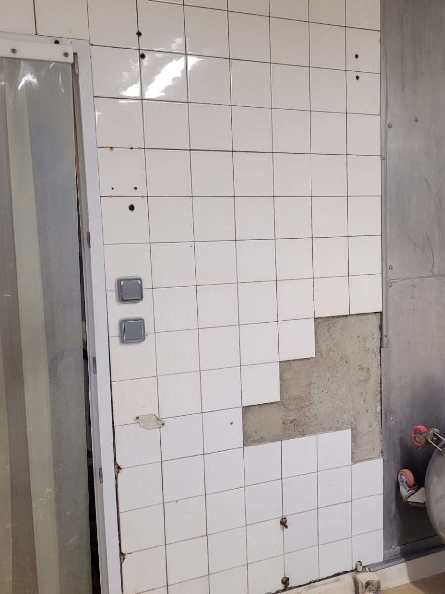 Mur en faïence dont plusieurs carreaux se sont descellés, support à nu, en cuisine collective