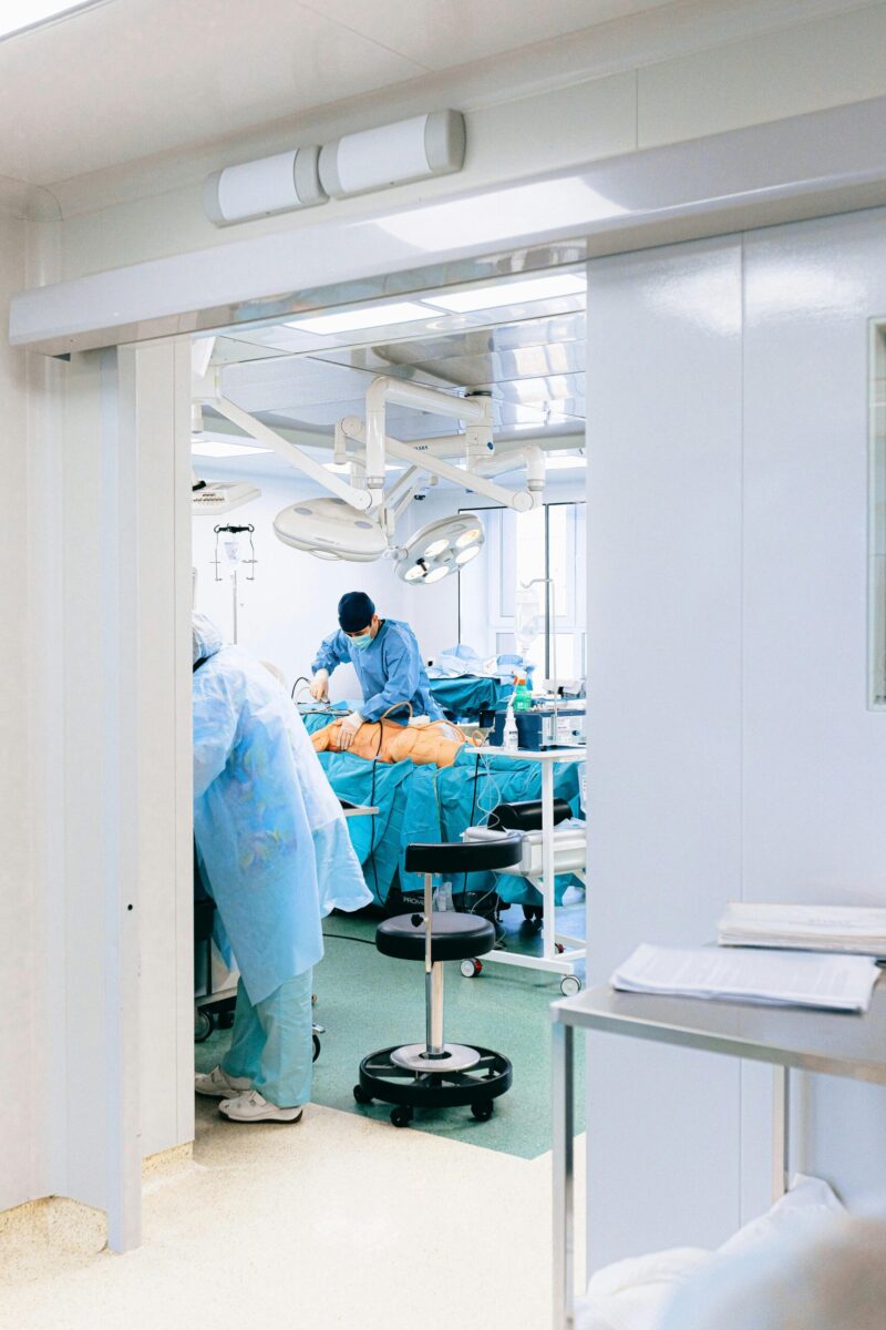 A team of surgeons perform an operation in a bright, sterile operating room setting.